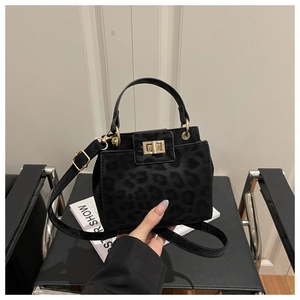 Detail of black leopard print suede handbag with gold lock and metal handle