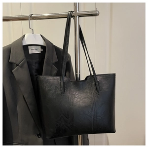 Detail of black faux leather tote bag with vintage texture hanging on a metal hanger