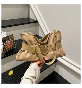 Détail du sac cabas plissé beige avec boucle dorée et chaîne sur un escalier épuré