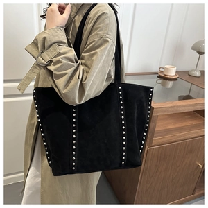 Détail du grand sac cabas en daim noir avec rivets argentés porté à l'épaule