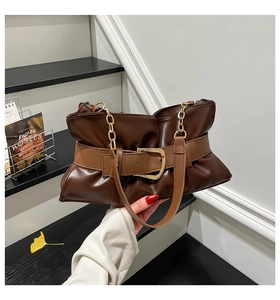 Détail du sac cabas en cuir marron avec plis souples, boucle de ceinture et chaîne dorée