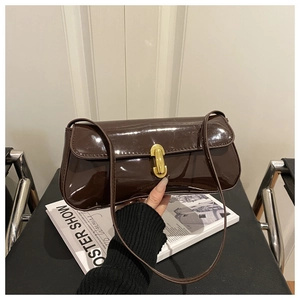 Gros plan du sac porté épaule en cuir verni marron avec boucle métallique dorée