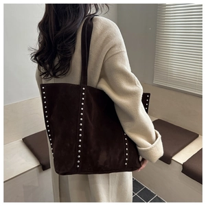 Détail d'un grand sac cabas en daim marron avec des clous argentés et un style vintage