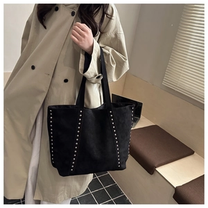 Close-up of black suede tote bag featuring silver rivet studs and durable shoulder straps