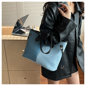 Modern tote bag featuring blue denim patchwork and black leather straps in an office setting