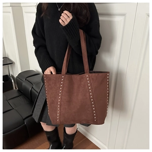 Close-up of dark brown suede tote bag featuring silver rivet studs and retro texture
