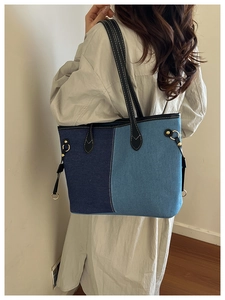 Detail of denim patchwork tote bag with contrast stitching and golden metal hardware