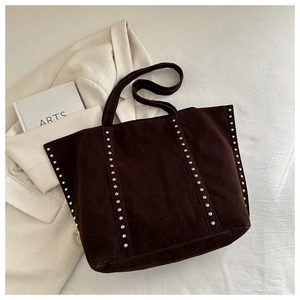 Détail du sac cabas en daim marron avec clous argentés verticaux et doubles anses