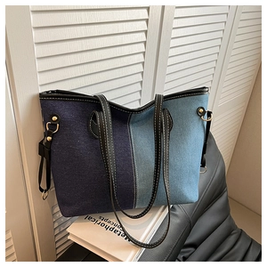 Detail of denim patchwork tote bag with black leather straps and gold metal hardware