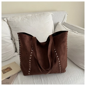 Detail of vintage brown suede tote bag featuring silver studs on soft textured surface