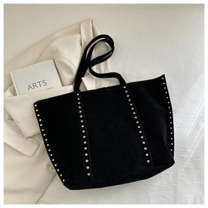 Détail d'un sac cabas en daim noir avec clous argentés et design spacieux moderne