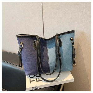 Macro view of denim patchwork tote bag with leather straps and golden hardware details