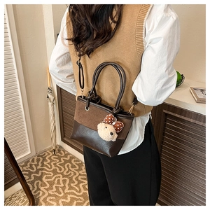 Detail view of stylish two-tone bucket bag with adjustable strap and cute bear charm