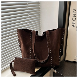 Détail macro du sac cabas en daim marron avec des rivets métalliques argentés sur la sangle