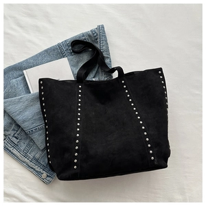 Detailed close-up of a black faux suede tote bag featuring silver rivet hardware accents
