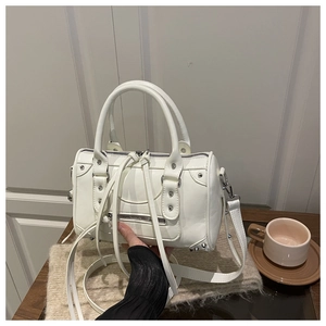 Detail of white leather boston bag featuring metallic studs and long zipper tassels