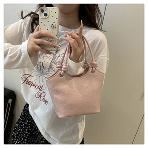 Detail of pink PU leather handbag with embossed cartoon patterns and knotted strap