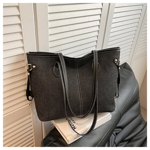 Close-up of black denim tote bag with contrast white stitching and gold hardware detail