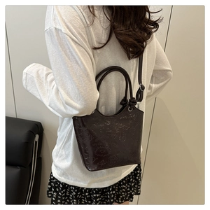 Detail of dark brown leather crossbody bag with cartoon embossed patterns and dual handles