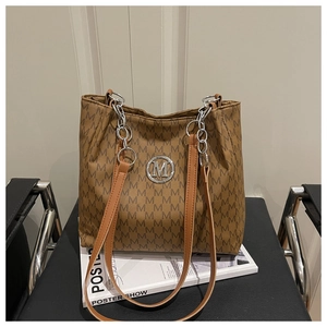 Détail du cabas à imprimé monogramme M avec logo argenté et bandoulière en cuir brun