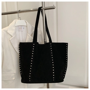 Détail du sac cabas en daim noir avec rangées verticales de clous métalliques argentés