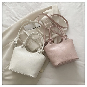 Detailed view of embossed cartoon patterns on white and pink leather bucket bags