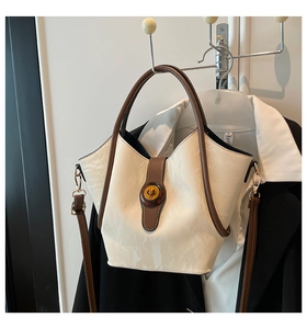 Detail of cream marbled bucket bag with brown handles hanging in a closet setup