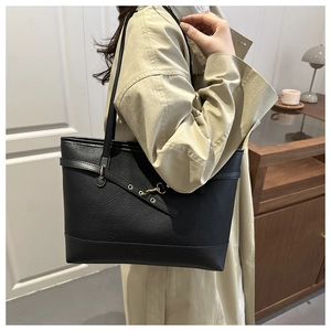 Side view of large black textured leather tote bag with gold hook buckle on a model
