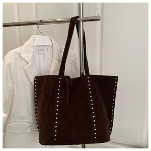 Détail du sac cabas en daim marron foncé avec clous métalliques et style industriel rétro