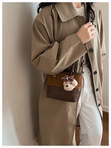 Detail of vintage bicolor bucket bag with cute plush bear charm on adjustable strap