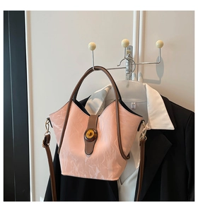 Detail of light pink bucket bag in glossy patent leather with brown handles and strap