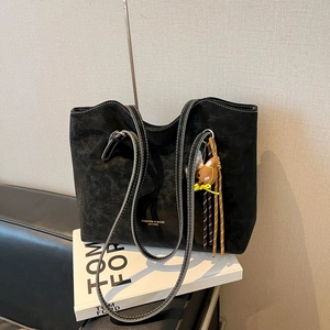 Black suede tote bag with contrast stitching, long straps, and a cute bear charm