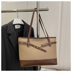 Detailed close-up of textured two-tone tote bag with leather straps and gold buckle