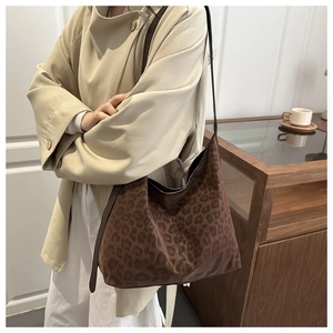 Close-up of leopard print hobo bag with textured fabric and wide brown strap