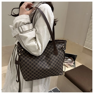 Detail of coffee brown tote bag with all-over M letter monogram and gold hardware