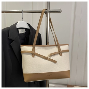 Macro detail of lychee grain leather tote bag with gold hardware and brand logo