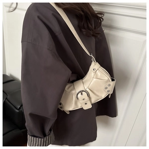 Detail of cream pleated leather crescent bag featuring vintage silver buckle and rivets