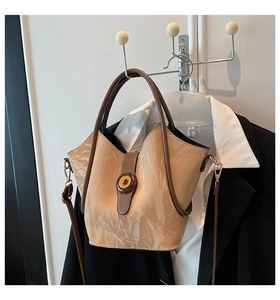 Detail of light khaki pleated texture handbag with dark brown trim and twist lock closure