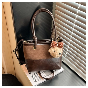 Nahaufnahme der Vintage-Eimertasche aus braunem Materialmix mit süßem Bärenanhänger
