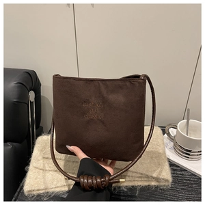 Close-up of brown suede bucket bag with fashion lettering and stylish knotted strap detail