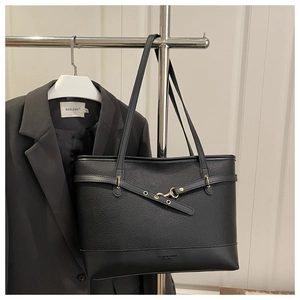 Detail of black pebbled leather tote bag with gold hardware and cross-strap design