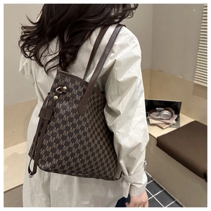 Detail of dark brown tote bag with M letter monogram print and gold metal drawstring buckles