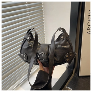 Detailed view of black motorcycle half-moon bag with silver studs and metal buckle