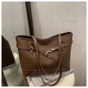 Close-up of brown litchi grain leather tote bag featuring a gold buckle and dual handles