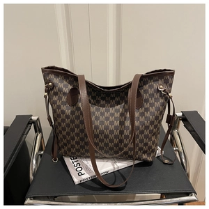 Close-up of brown tote bag with classic M-letter monogram pattern on a designer chair
