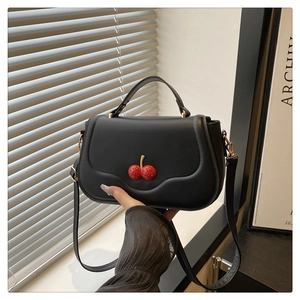 Detail of matte black crossbody bag featuring unique 3D red cherry embellishment