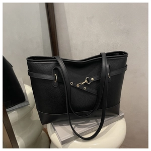 Detail of black pebbled leather tote bag with gold hardware in a modern home setting