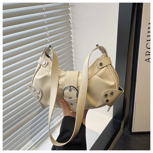 Macro detail of beige pleated shoulder bag featuring silver buckle and metal rivets