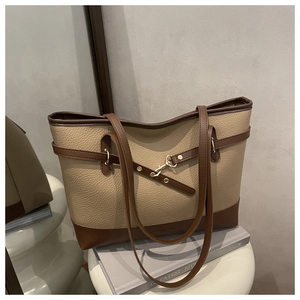 Detail of beige lychee texture tote bag with brown leather strap and metal buckle