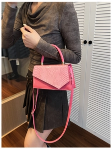 Detail of pink patchwork handbag featuring crocodile texture and rounded top handle